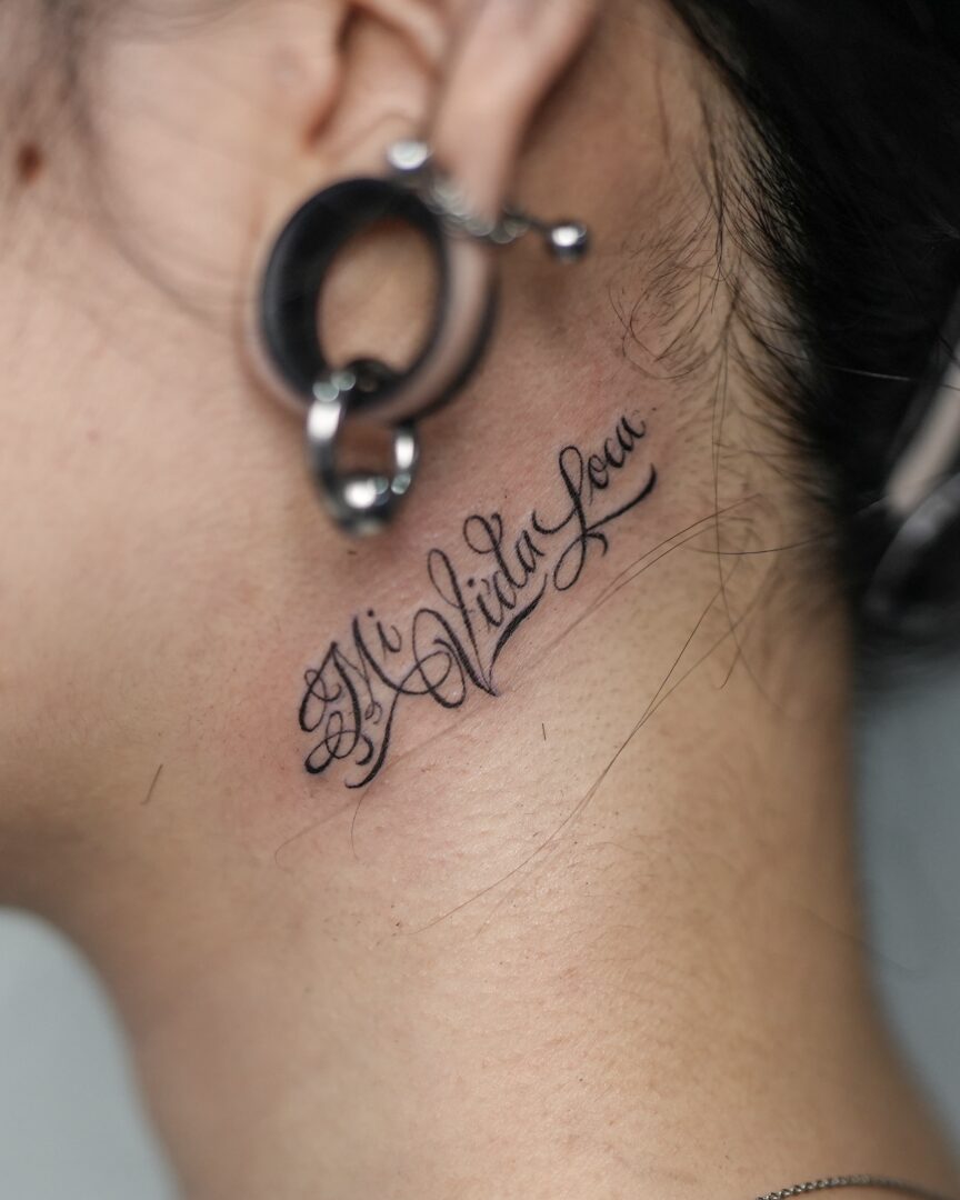 女性の耳裏にレタリングタトゥー